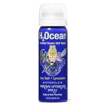 PARIS, FRANCE - MARCH 06: Lous & The Yakuza wears gold embossed LV monogram pattern sunglasses from Louis Vuitton, gold earrings, a silver nose piercing, a pale green and pale blue embroidered ruffled silk / satin sleeveless tank-top from Louis Vuitton, o