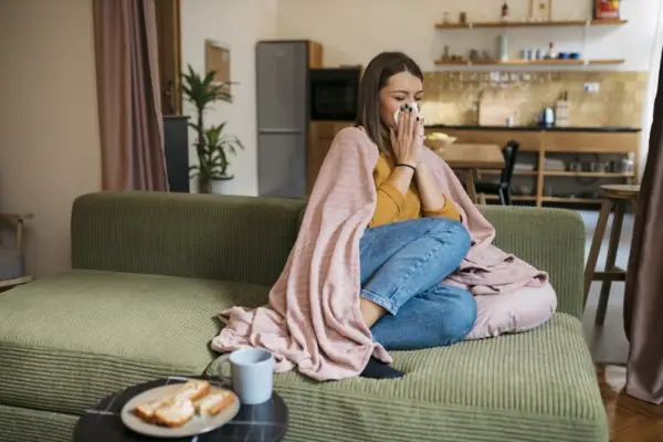 Woman sick on the couch, deciding what foods to eat when sick.