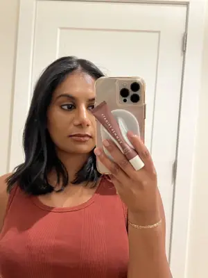 Woman holding an iPhone with the Case-Mate Glossy MagSafe Lip Gloss Holder attached.