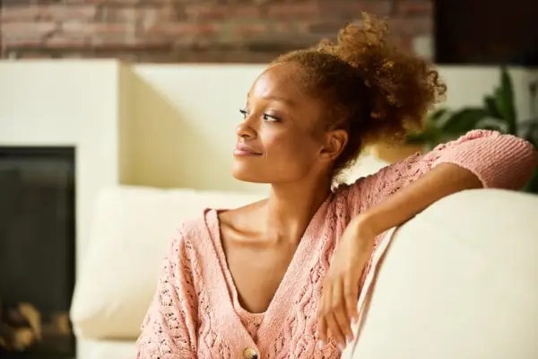 Young Woman in Living Room With Elbow on Couch