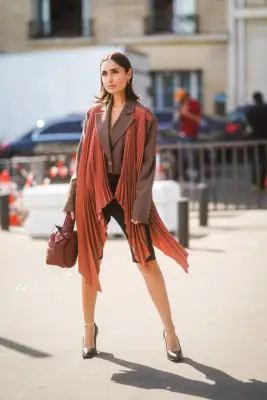 Style Black Shorts With a Brown Jacket, Orange Vest, and Black Heels