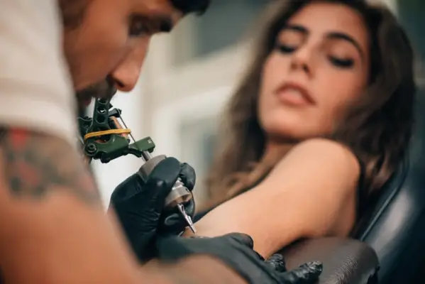 Tattoo artist creating a tattoo on a girl