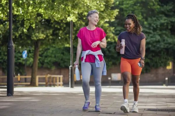 Two women going for a hot girl walk outdoors.